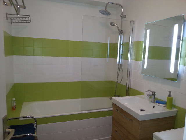 Vue de notre salle de bain couleur blanche et vert anis. Baignoire. Meuble vasque et lave linge